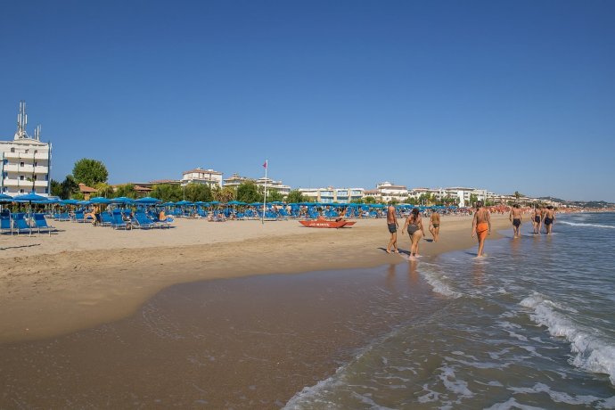 San Benedetto del Tronto: spiaggia dorata, ombrelloni blu e mare Adriatico calmo, giornata estiva.