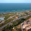 Vista aerea di una località costiera, con autostrada e città storica vicino al mare.