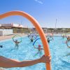 Istruttrice di acquagym in piscina guida gruppo con tubi galleggianti colorati.