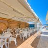 Ristorante all'aperto con tavoli e sedie bianche sotto tende, vicino al mare.