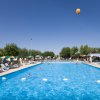 Una grande piscina all'aperto con lettini e ombrelloni colorati.