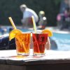 Due bevande rosse con fette d'arancia e cannucce, a bordo piscina.