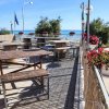 Terrazza con tavoli di legno e vista mare, decorata con fiori colorati.