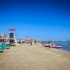 Spiaggia con lettini verdi, torre di salvataggio, alcune persone in acqua e vista sul mare limpido.