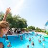 Una persona saluta vicino a una piscina affollata.