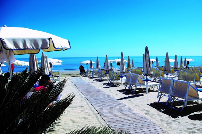 Spiaggia con file di ombrelloni chiusi.