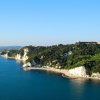 Costa rocciosa con scogliere bianche e vegetazione, vista sul mare.