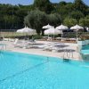 Piscina con lettini e ombrelloni bianchi.