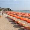 Spiaggia con numerosi ombrelloni arancioni e sdraio in file ordinate.