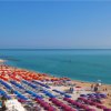 Una spiaggia con ombrelloni colorati e mare blu, vista dalla Riviera del Conero.