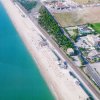 Vista aerea di una spiaggia con ombrelloni e mare blu.