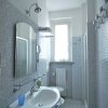 Un bagno stretto con un lavandino, specchio e finestra luminosa.
