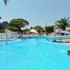 Piscina con scivolo e spruzzi d'acqua, circondata da palme e ombrelloni.
