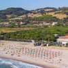 Spiaggia con ombrelloni colorati e colline sullo sfondo.