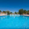 Una grande piscina azzurra circondata da sedie a sdraio bianche e ombrelloni arancioni.