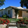 Un bungalow bianco con giardino e fiori rossi.