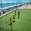 Gruppo di ragazzi gioca a calcio su un campo vicino alla spiaggia.