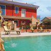 Piscina con cascata, lettini e edificio rosso sullo sfondo.