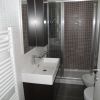 Bagno con doccia, lavabo rettangolare bianco, piastrelle marroni, e un termosifone verticale.
