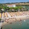 Veduta aerea di una spiaggia affollata con ombrelloni gialli.