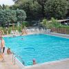 Piscina con persone che nuotano e altre sedute a bordo vasca.