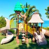 Un parco giochi con scivoli beige vicino al mare e palme.