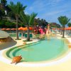 Piscina con scivoli, palme e decorazioni a tema tartaruga, ombrelloni arancioni sullo sfondo.