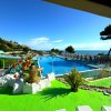 Piscina all'aperto con sdraio e ombrelloni rossi vicino al mare.