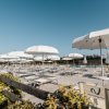 Lettini e ombrelloni bianchi su terrazza.