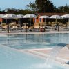 Piscina con getto d'acqua e ombrelloni bianchi.